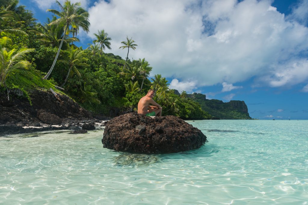 Gerben on a roch in front of the shore of Maupiti.